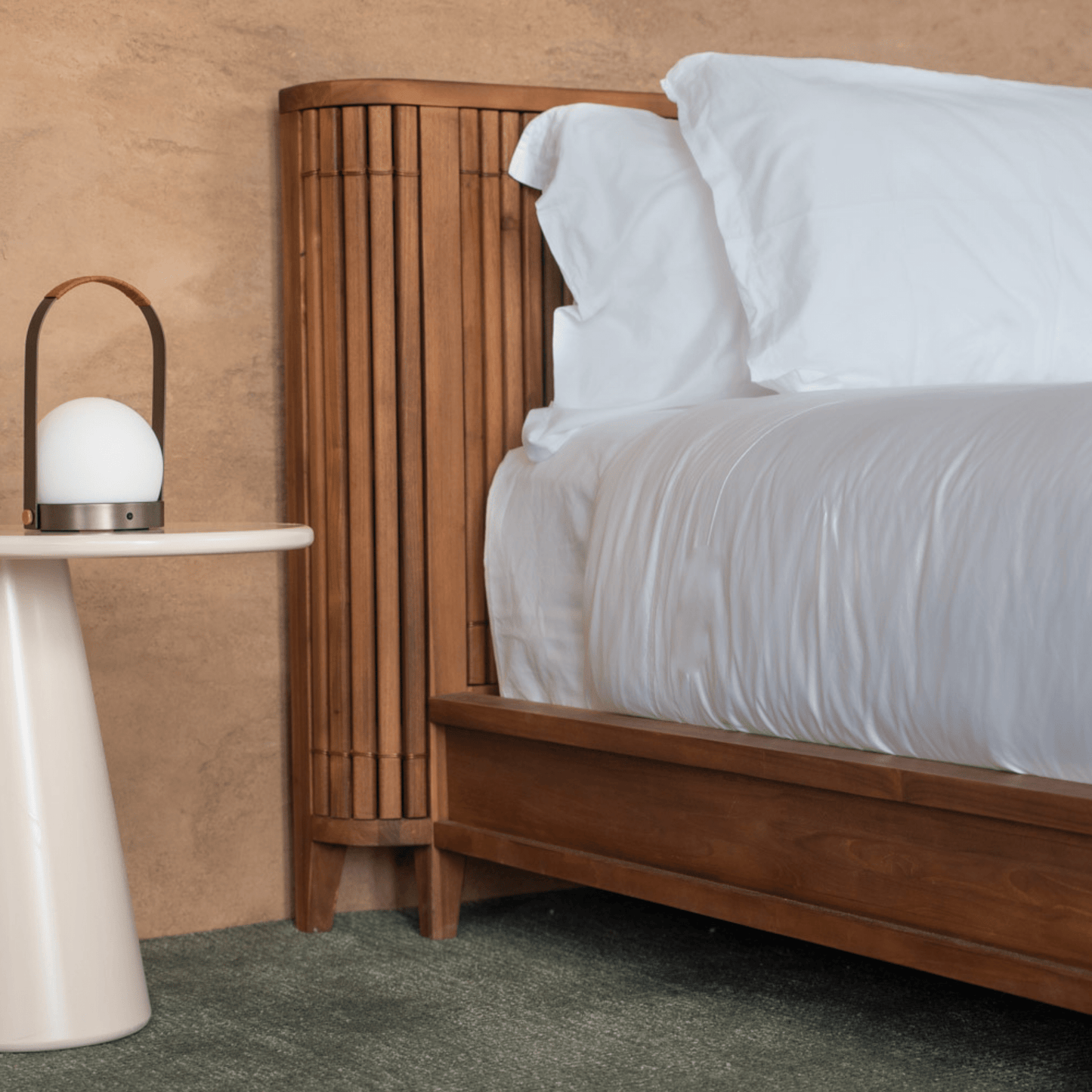 Bed with white bedding and lamp on a side table.