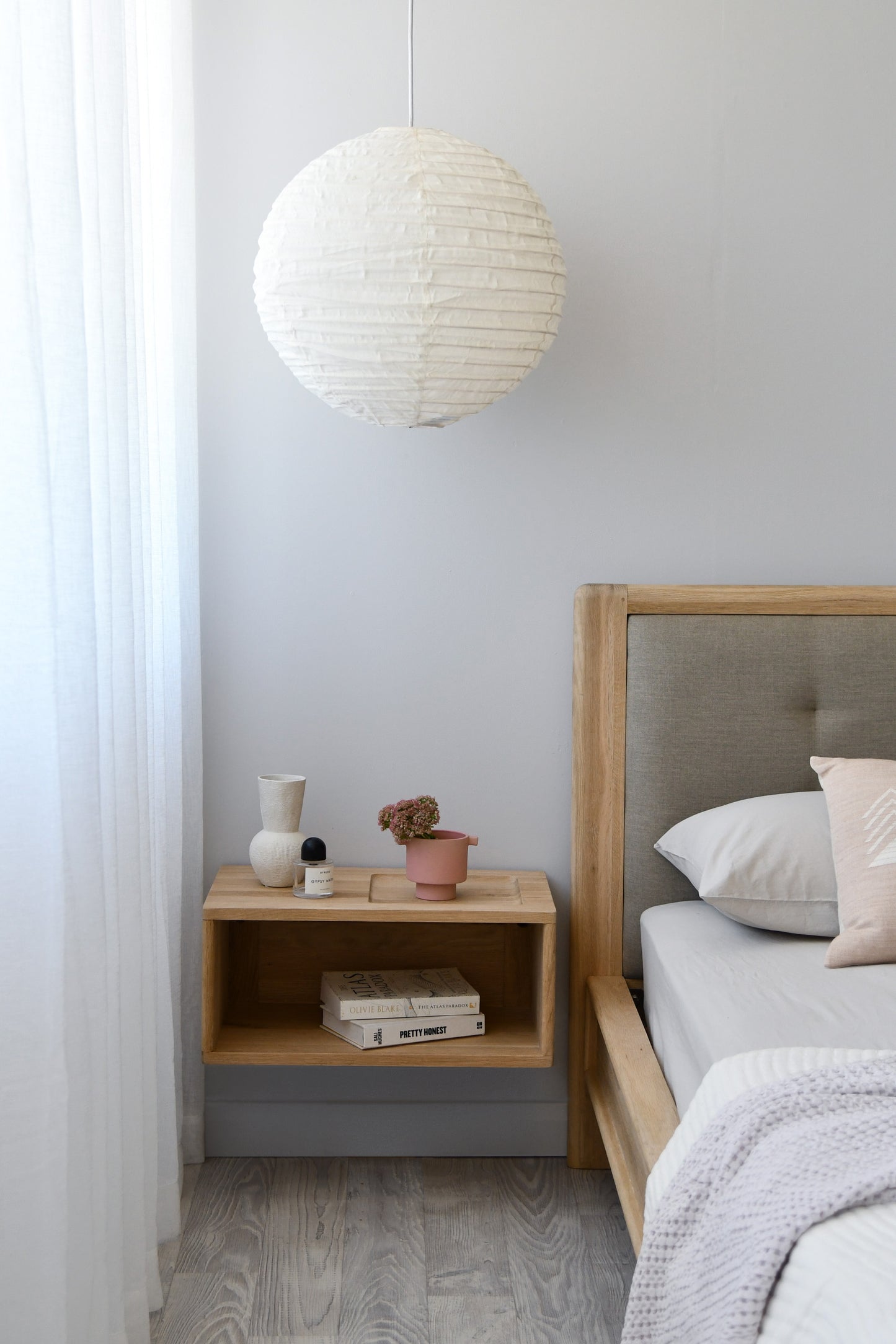Bedroom with paper lantern, nightstand, and bed.