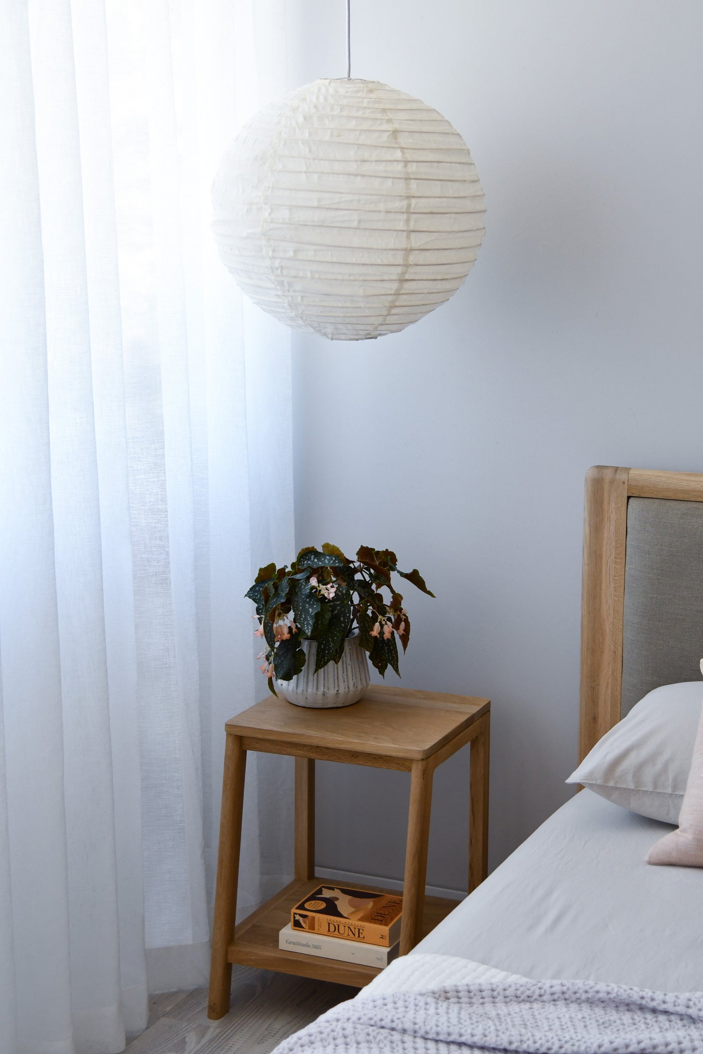 Bedroom with paper lantern and plant on nightstand