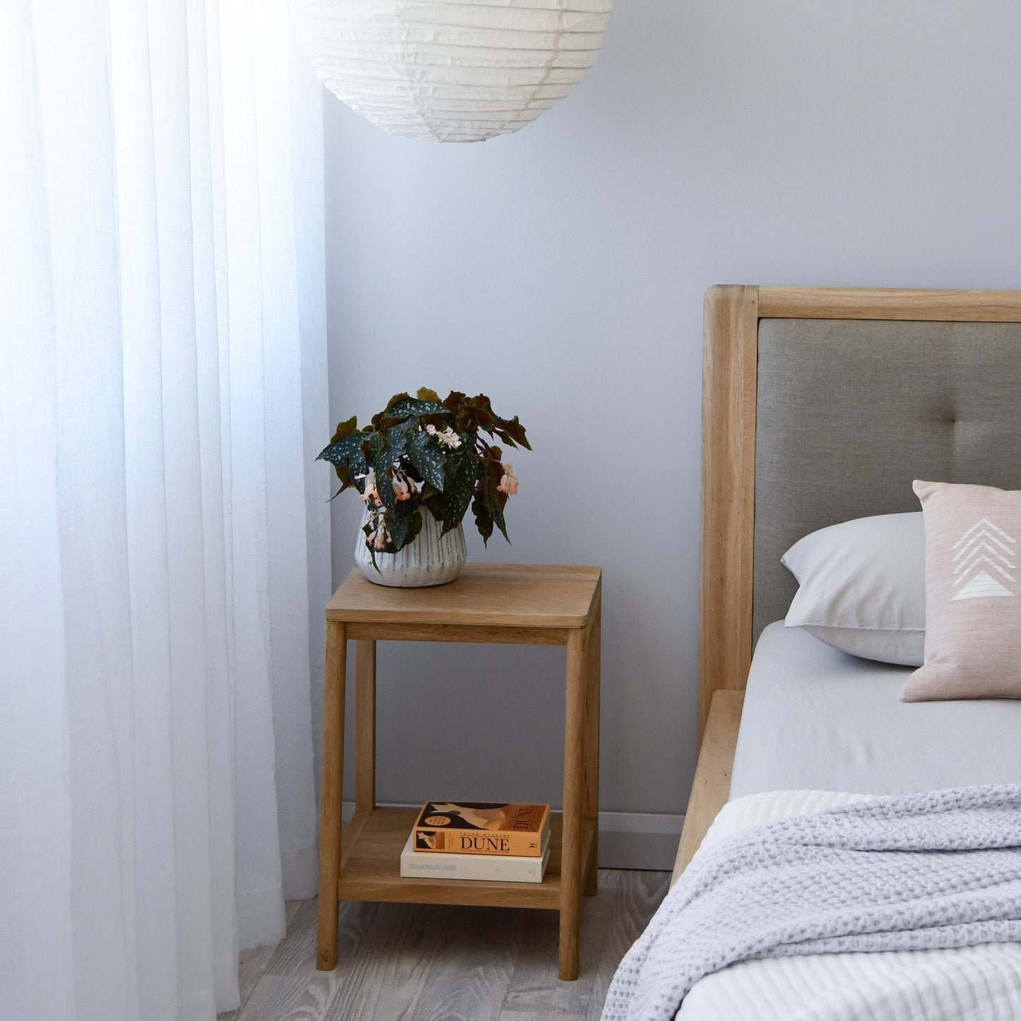 Bedroom nightstand with plant, book, and bed (KCC24OKCC41O_4)
