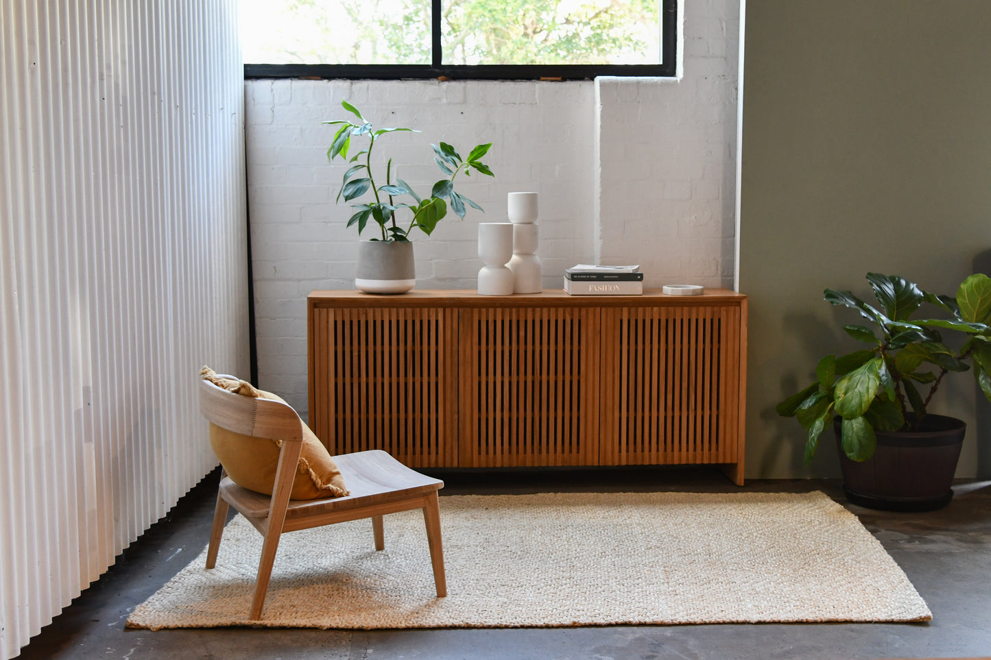 Wooden cabinet and chair in a room with plants.