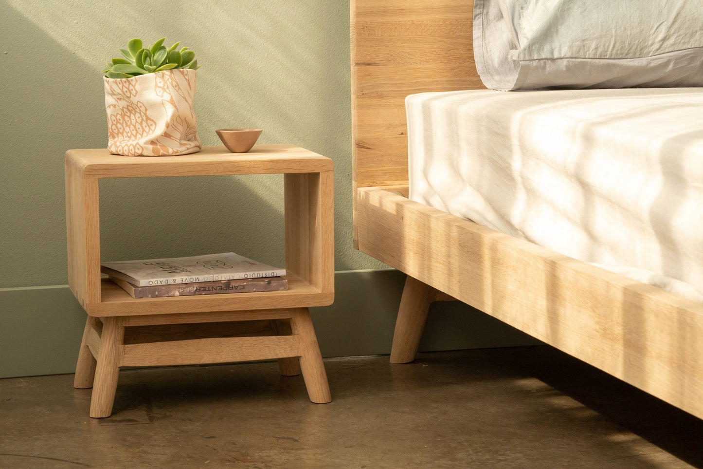 KT034OKT031O nightstand with plant, bowl, and book next to bed