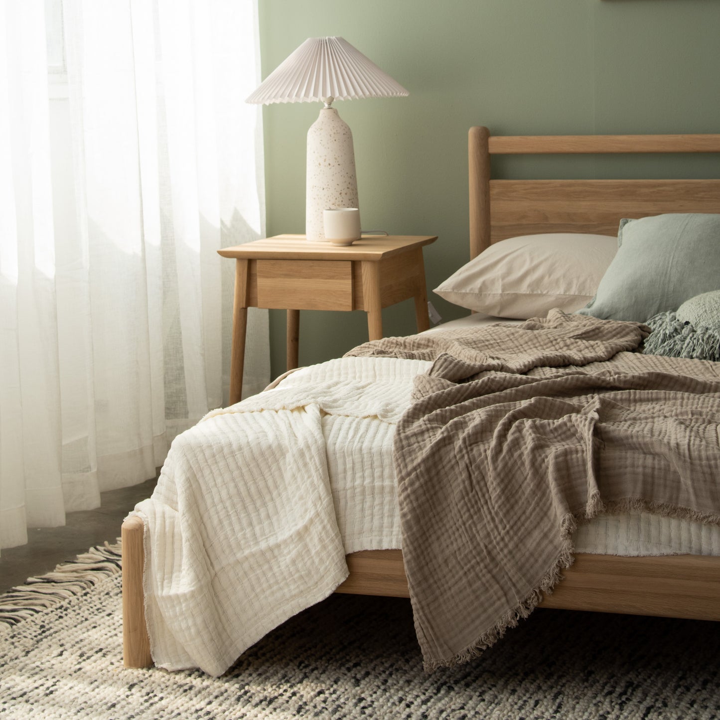 Bedroom with wooden bed, lamp, and neutral bedding