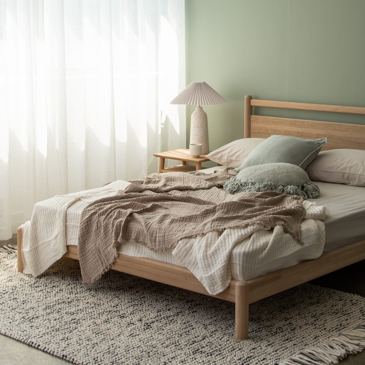 Bedroom with wooden bed, neutral bedding, and rug.
