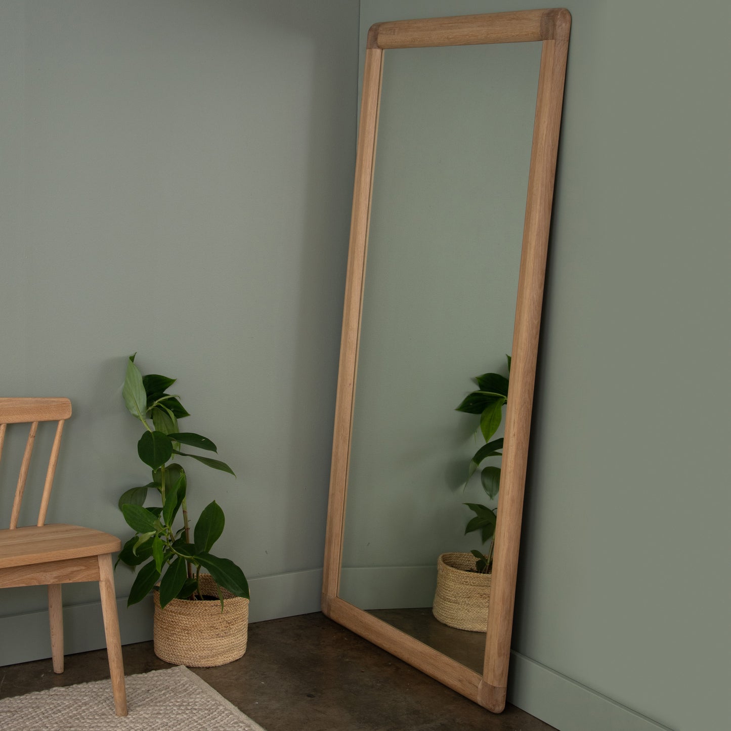 Wooden floor mirror in corner with plants.