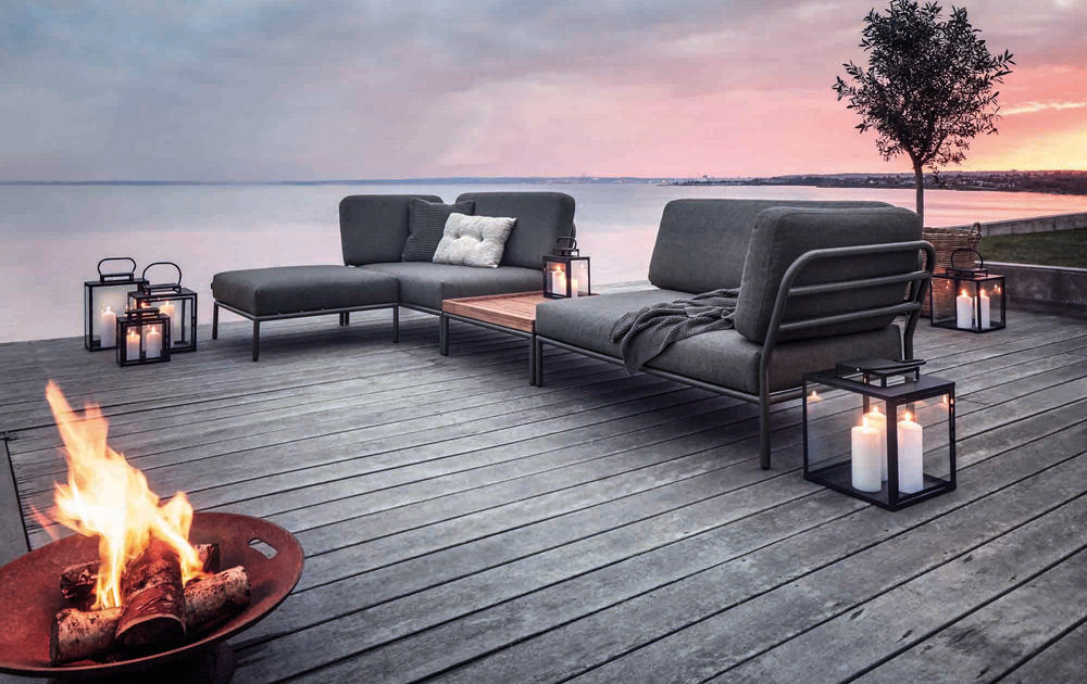 Outdoor lounge setting with fire pit and lanterns by the water