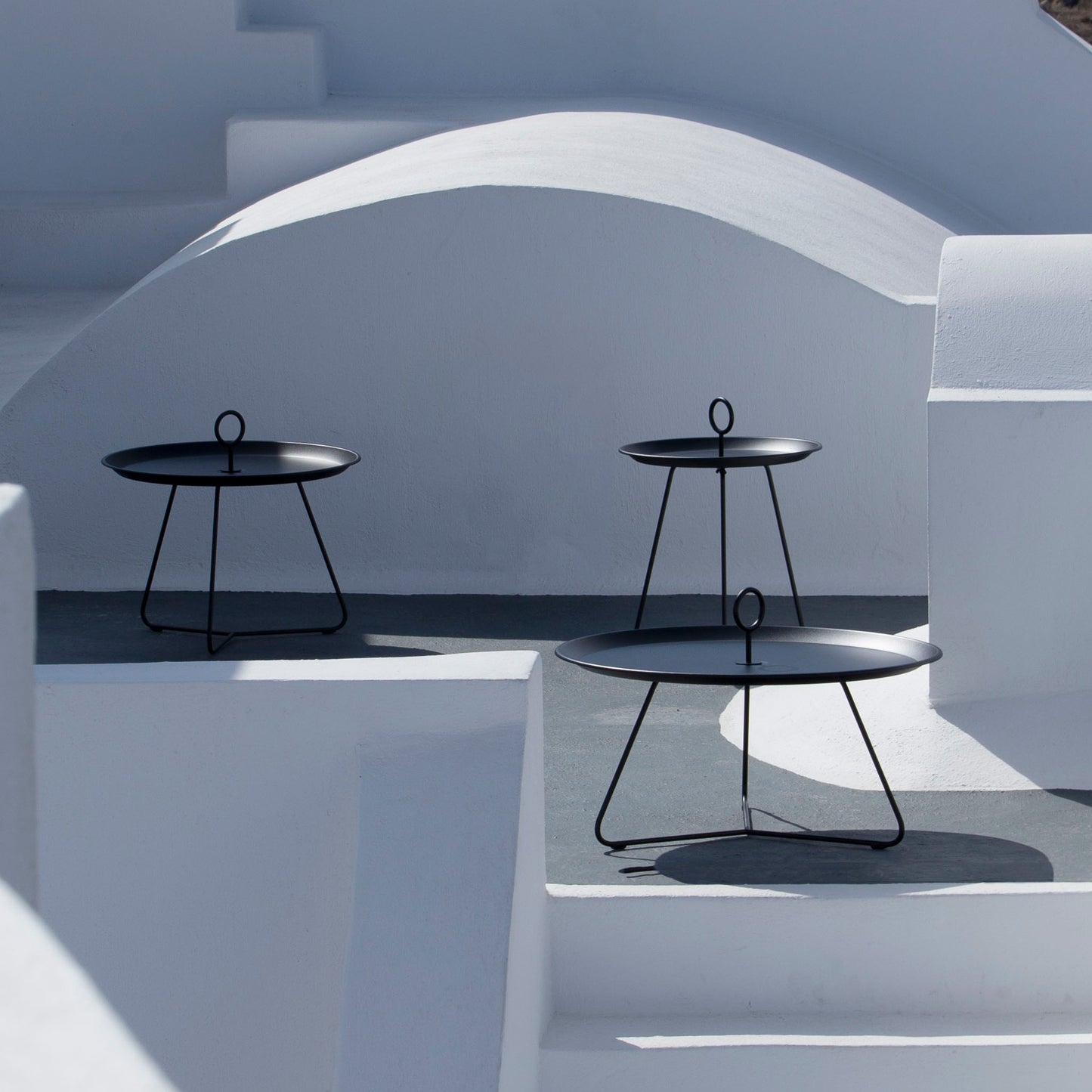 Three black outdoor side tables on white steps