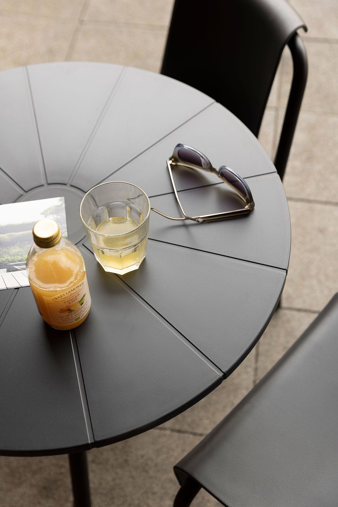 NAMI cafe table closeup with drink, sunglasses, and chair.