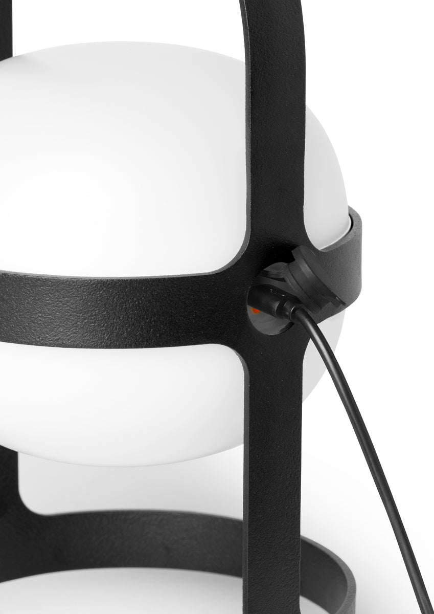 White globe lamp with black frame and charging cable.