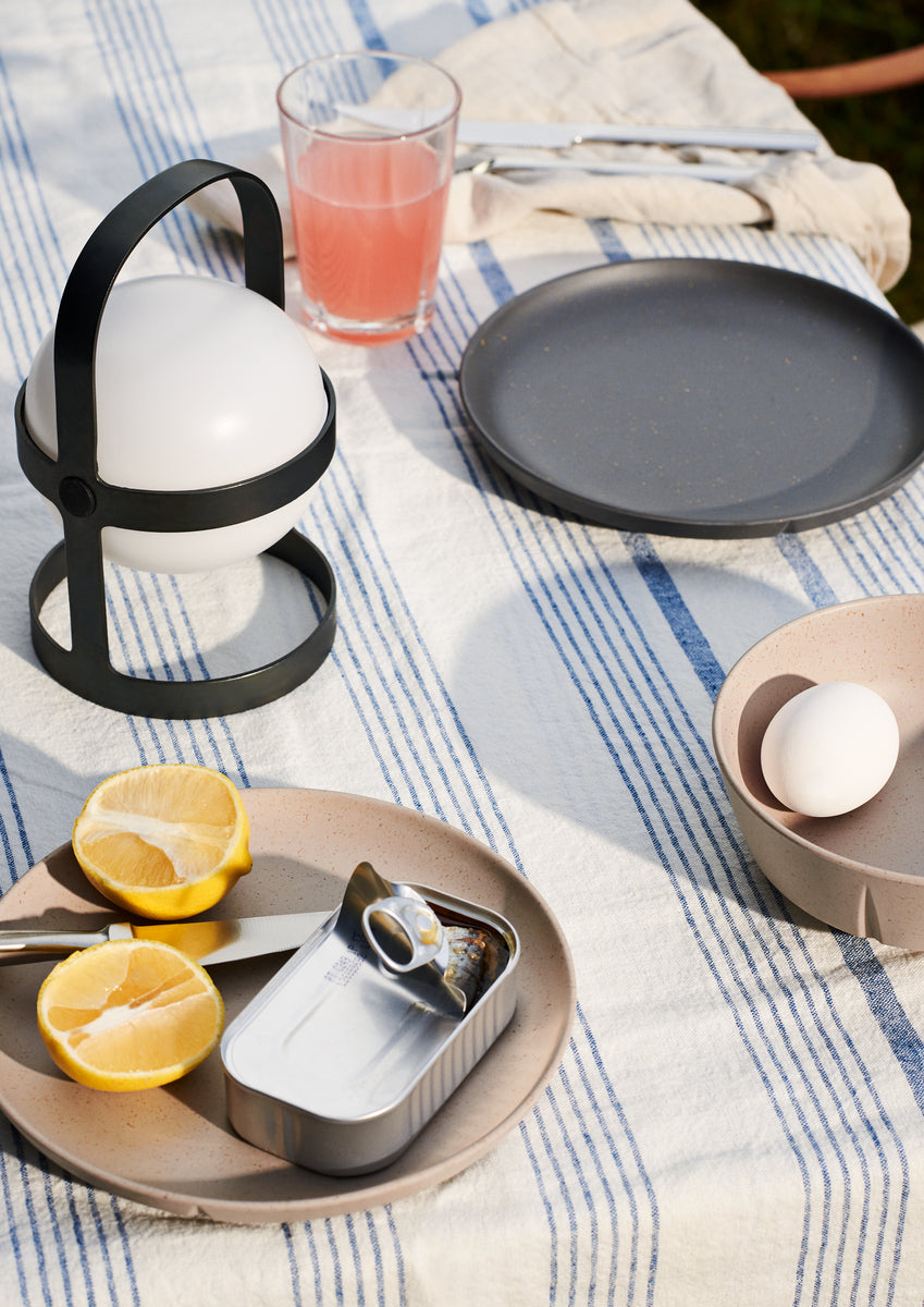 Outdoor dining setup with egg-shaped lamp, lemons, and plate.