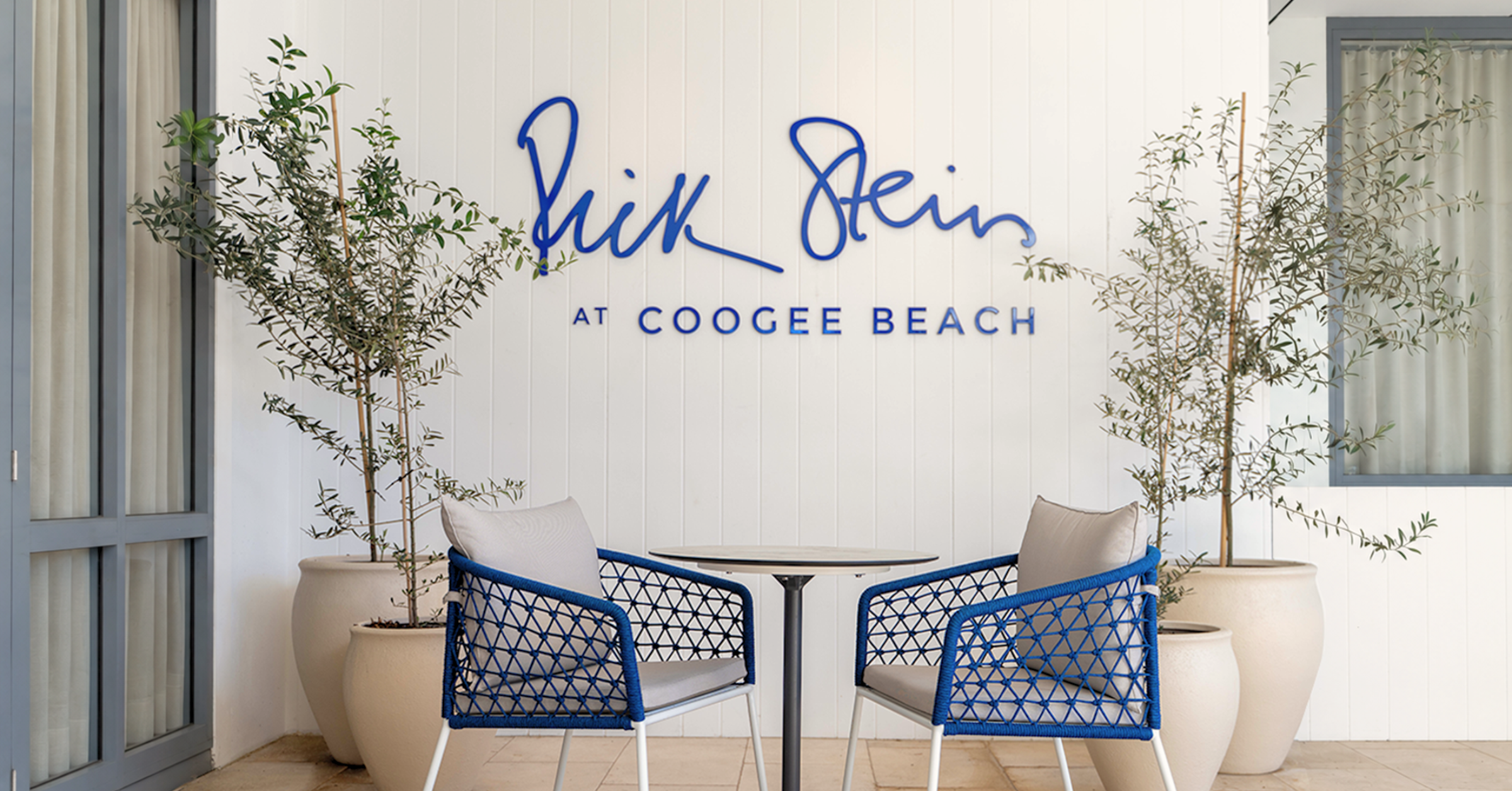 Rick Stein at Coogee Beach terrace with blue Mamagreen Ohana dining chairs and a round Glyph table.
