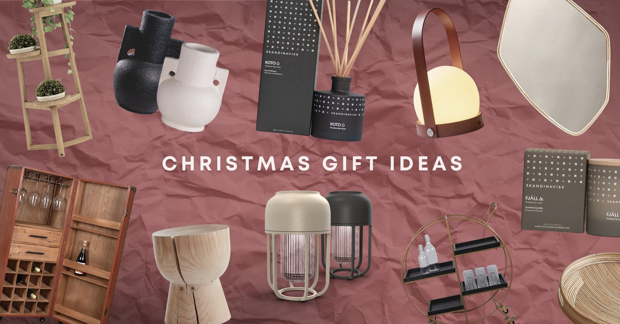 Christmas gift ideas featuring designer homewares including sculptural vases, Scandinavian candles and diffusers, portable lamps, mirrors, timber furniture and a bar trolley on a textured blush background.