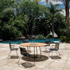 Patio furniture set around a round table near a pool.