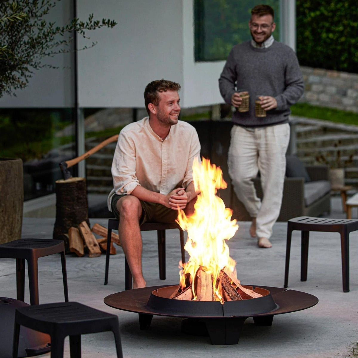 Outdoor fire pit with two men enjoying the flames
