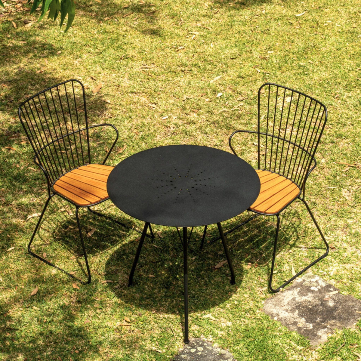 Black patio table and two chairs on grass.