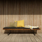 Wooden bench with pillows and blanket.