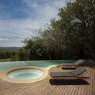 Pool with lounge chairs and surrounding trees.