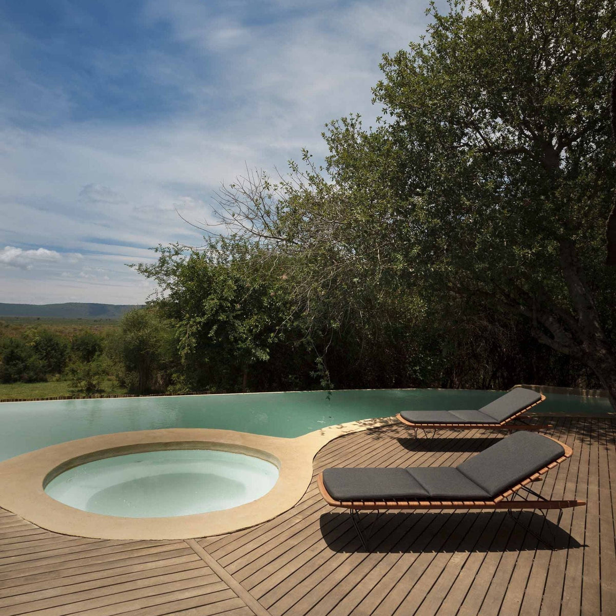 Pool with lounge chairs and surrounding trees.