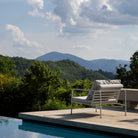 Lounge chair on a patio overlooking mountains and a pool.