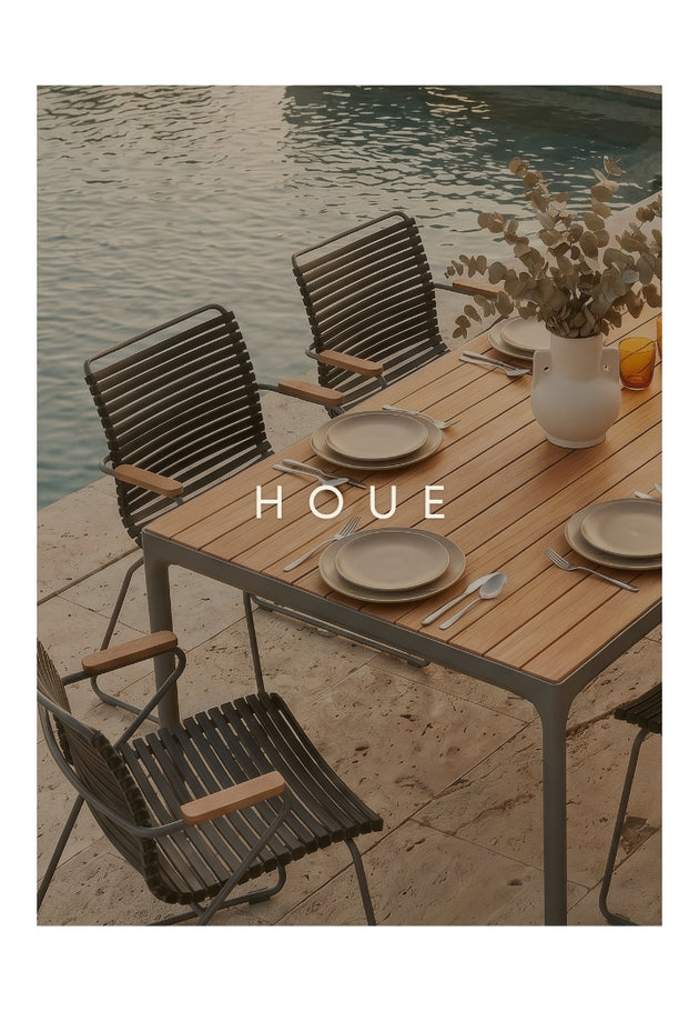 Outdoor dining set with table and chairs by a body of water, featuring the brand 'HOUE'.