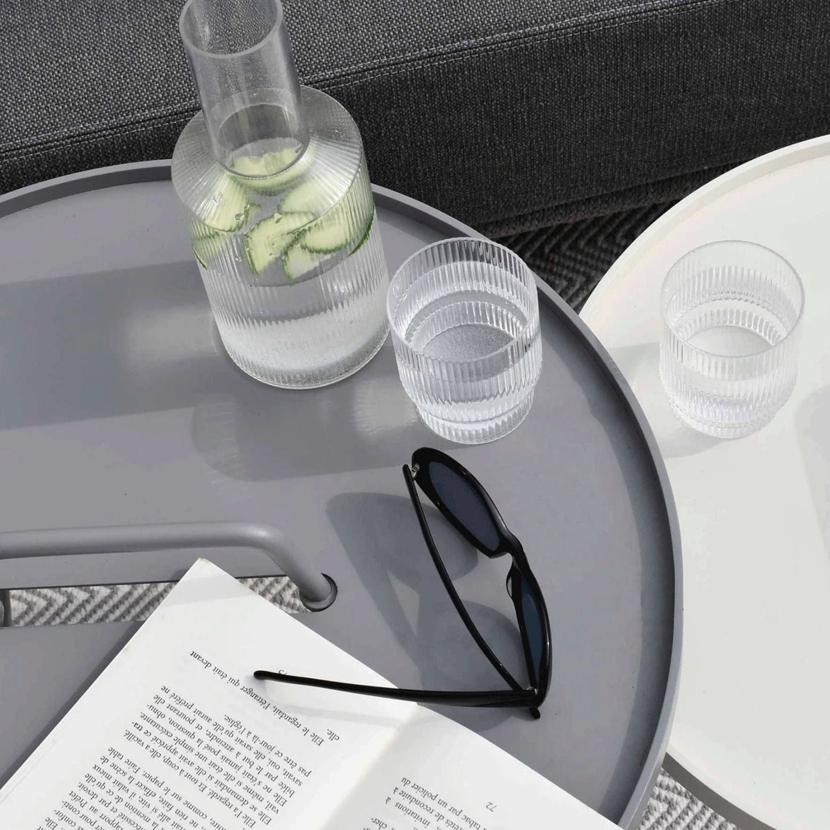 Modern table with water carafe, glasses, and sunglasses