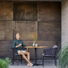 Man sitting at outdoor table with wood panel background