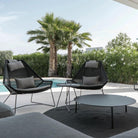 Modern patio chairs with coffee table and pool view.