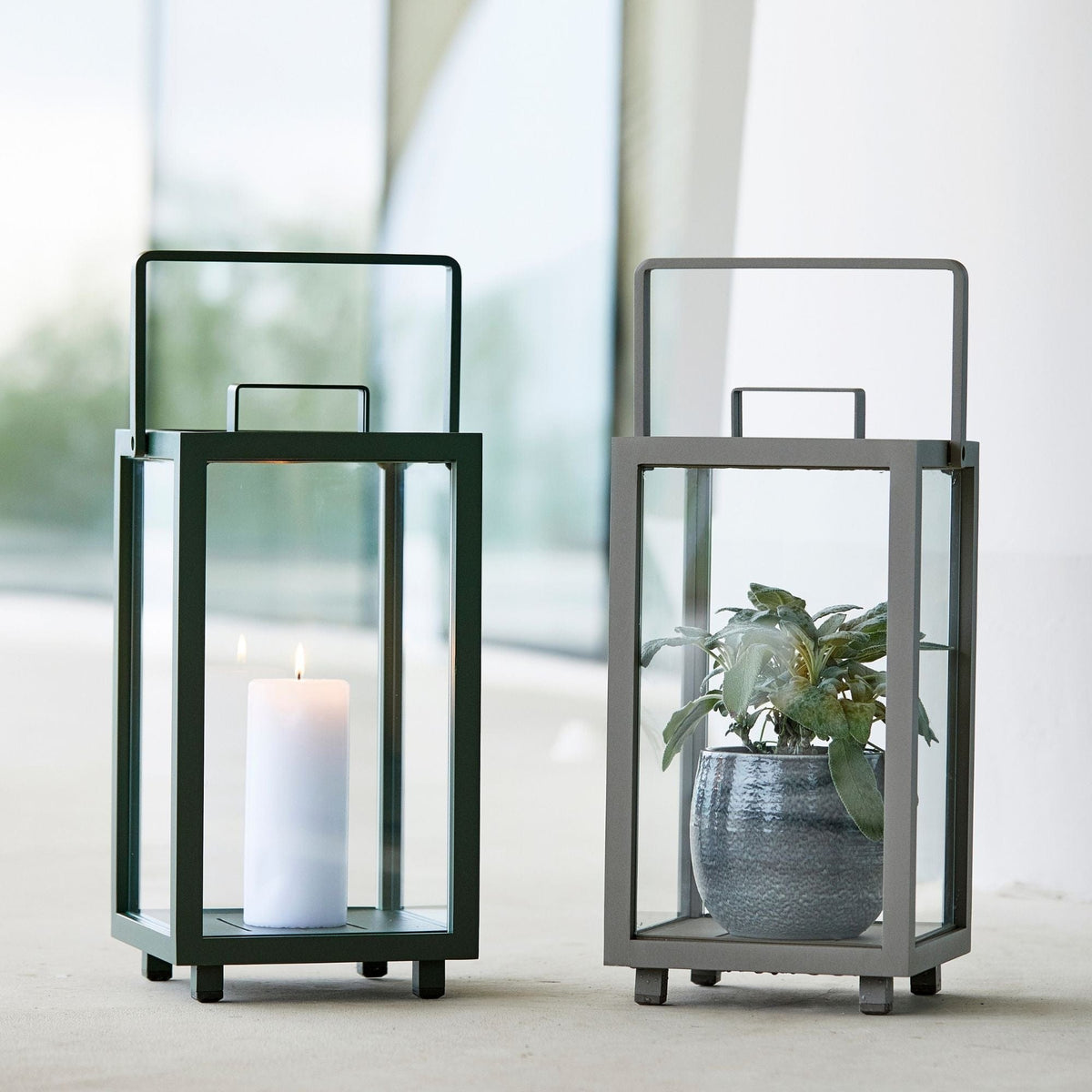 Two decorative lanterns, one with candle, one with plant.