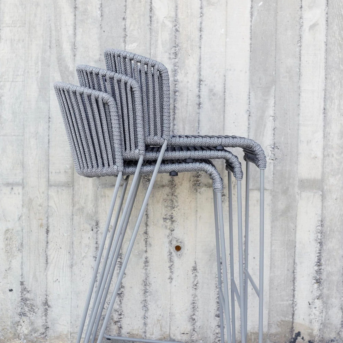 Stacked grey ROG chairs against concrete wall