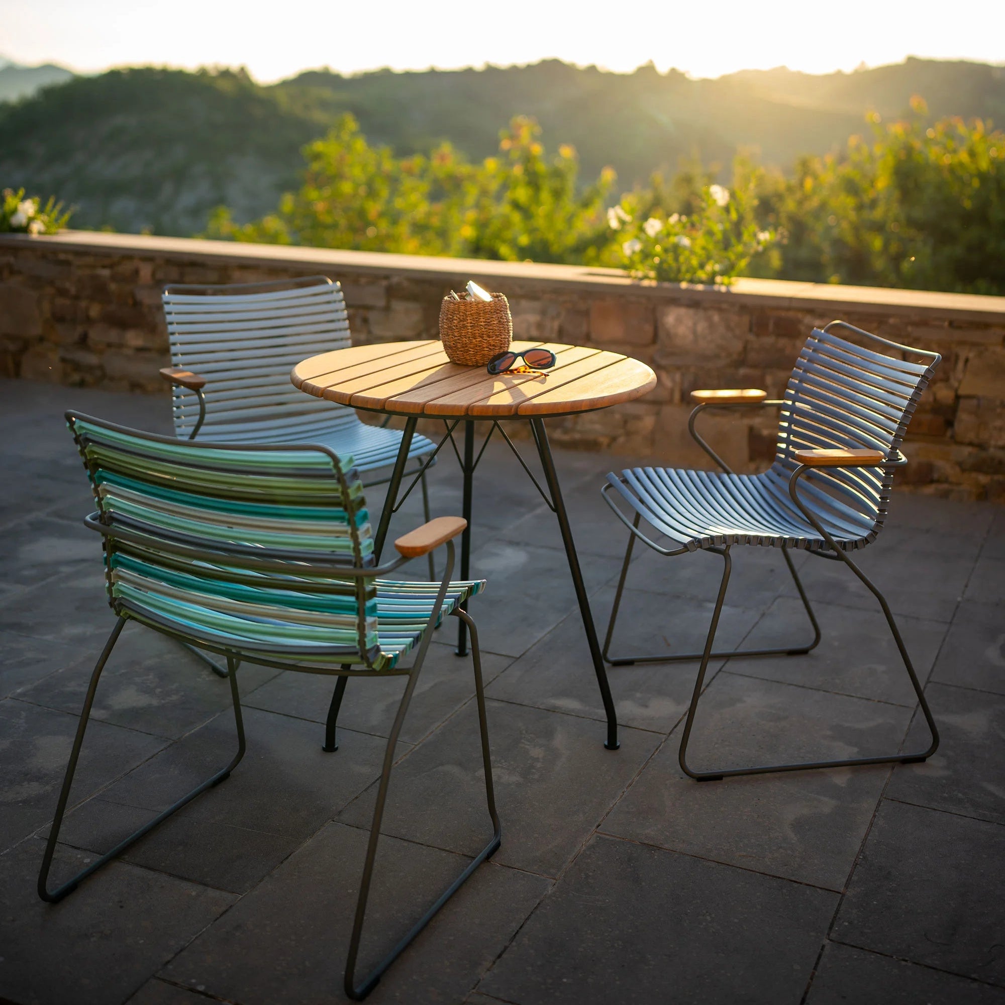 Outdoor setting with two chairs and a table on a stone patio overlooking a scenic landscape.