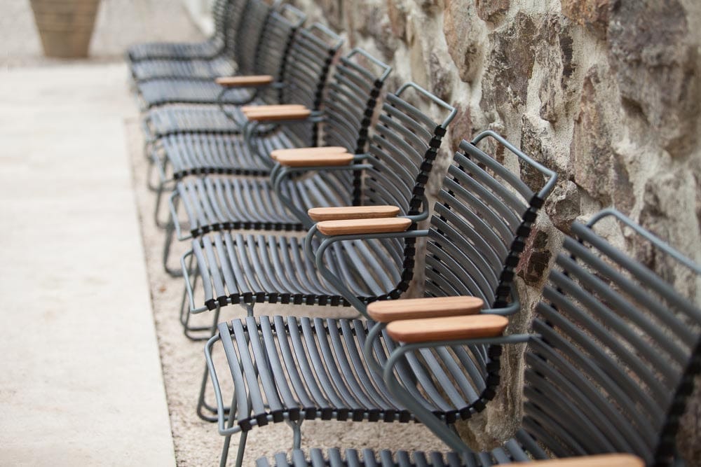 Black HOUE dining chairs in a row by a stone wall