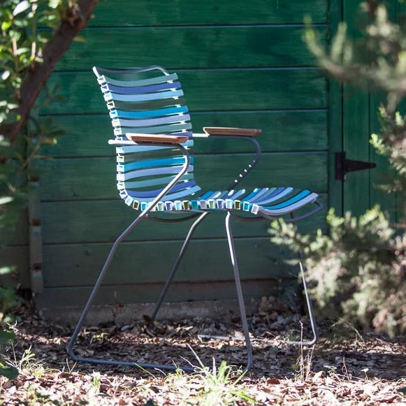 Blue and white striped chair in a garden setting with greenery.