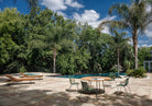 Olive green dining set on patio with palm trees