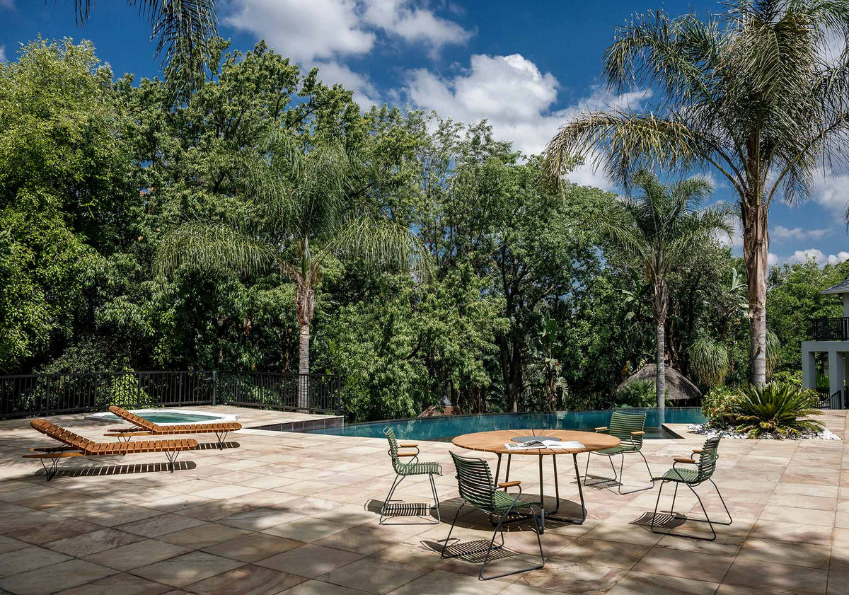 Olive green dining set on patio with palm trees