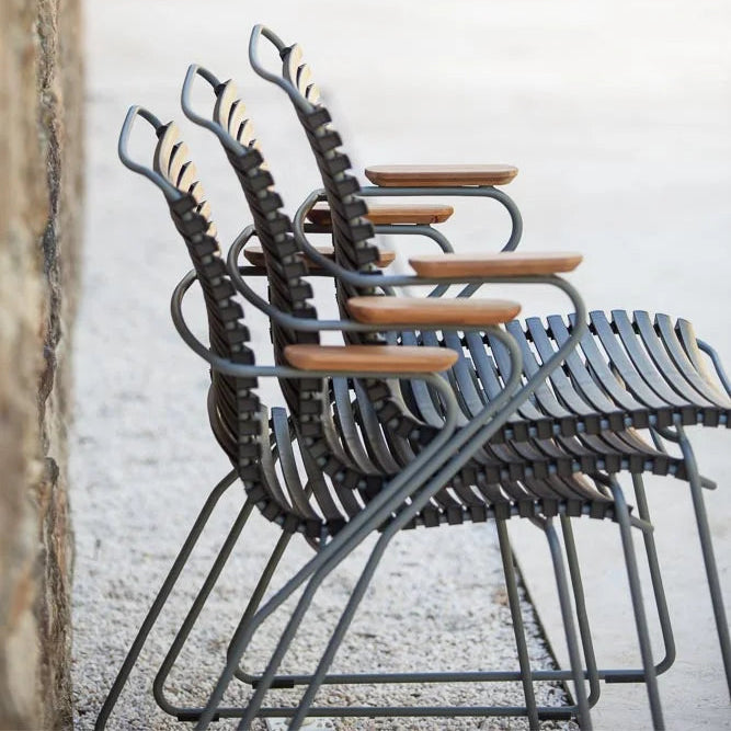 Stacked metal chairs with wooden seats against a white wall.