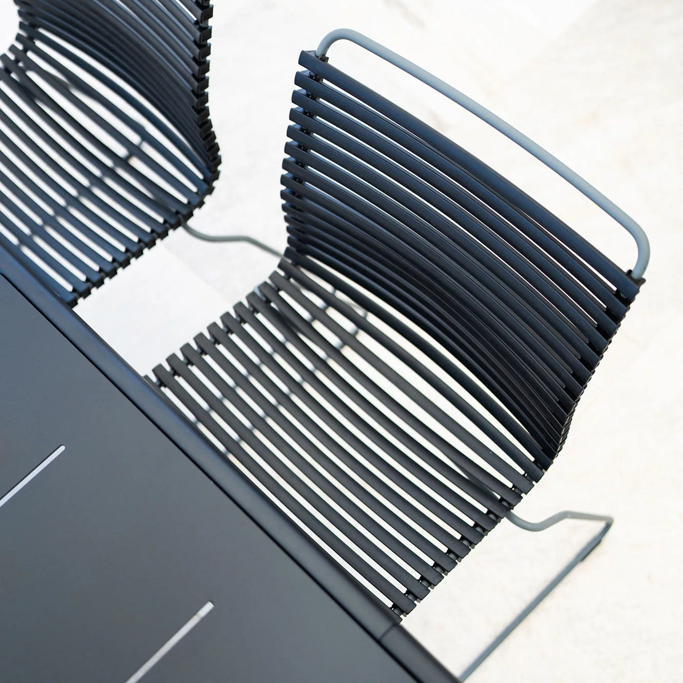 Stack of modern black chairs on a white floor