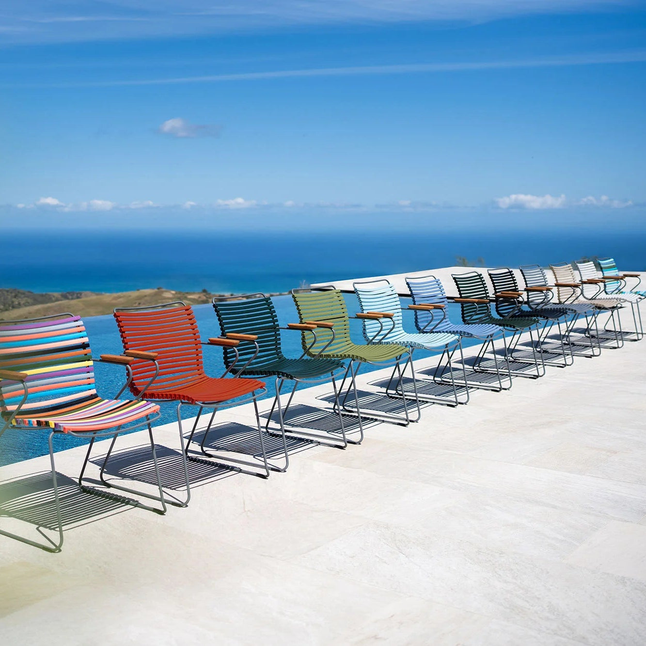 Colorful deck chairs lined up on a terrace with a scenic view of the ocean.