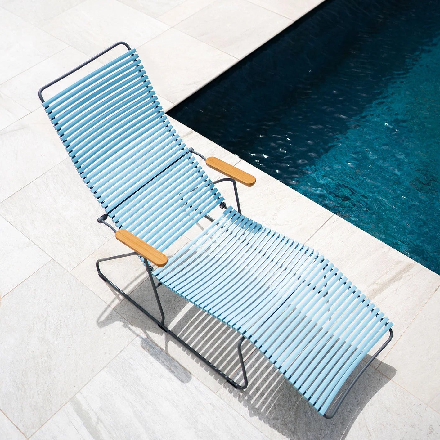 Blue lounge chair with wooden armrests by a pool
