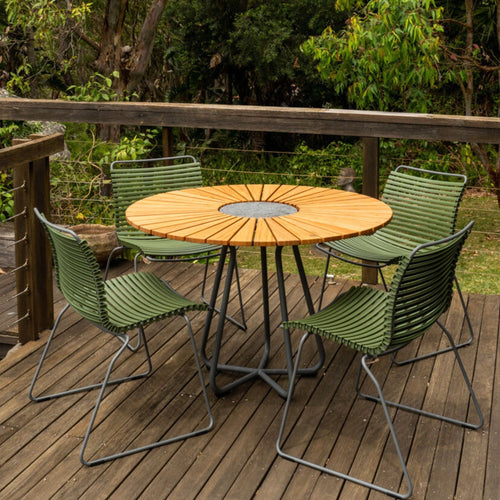 Round table with green chairs on deck