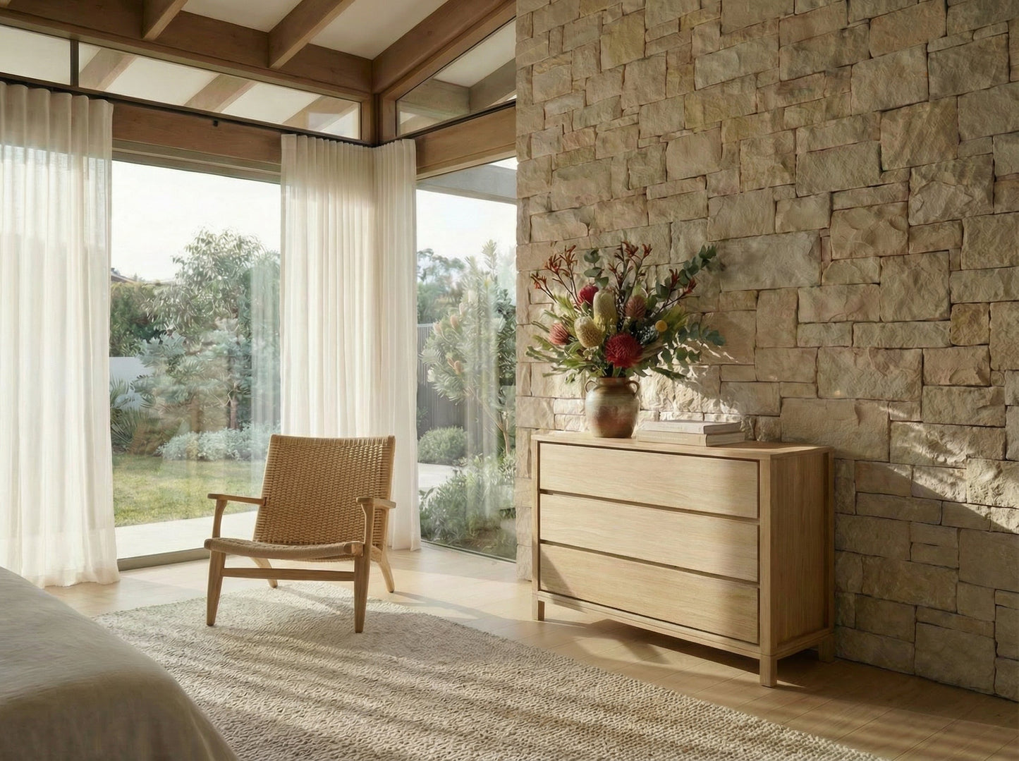 Modern bedroom with wooden dresser, chair, and stone wall.