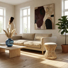 Modern living room with a beige sofa, wooden coffee table, and abstract art on the wall.