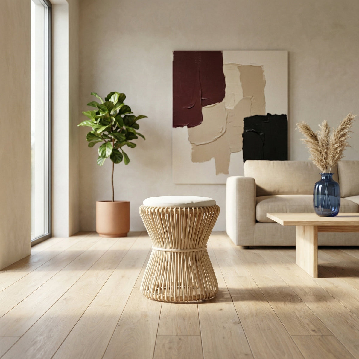 Modern living room with a neutral color palette, featuring a plant, ottoman, and abstract art on the wall.