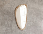 Asymmetrical wood-framed mirror on concrete wall
