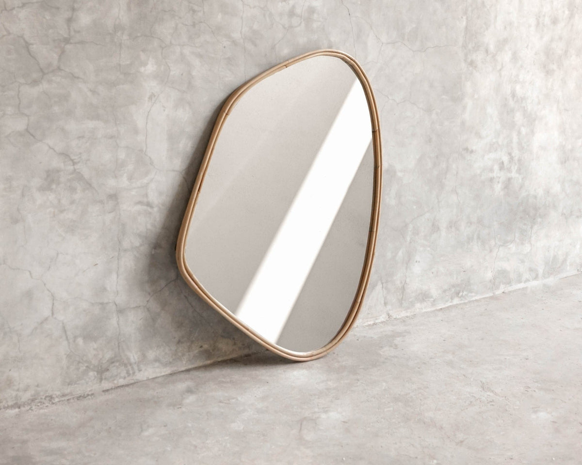 ELE125 Mirror with organic shape and gold frame against concrete wall.
