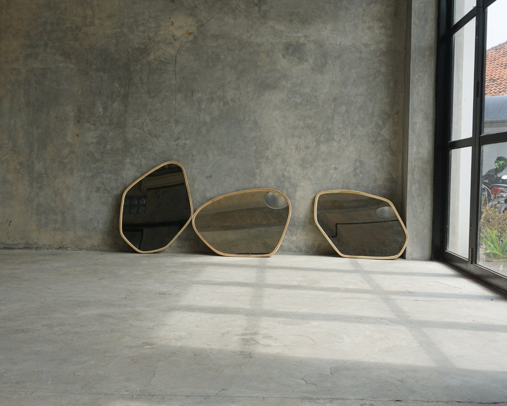Three abstract mirrors leaning against a gray wall