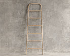 Wooden decorative ladder against a concrete wall.