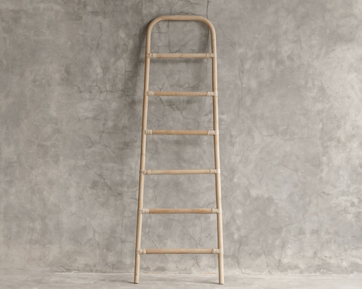 Wooden decorative ladder against a concrete wall.