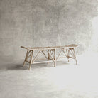 Woven rattan bench against a gray wall