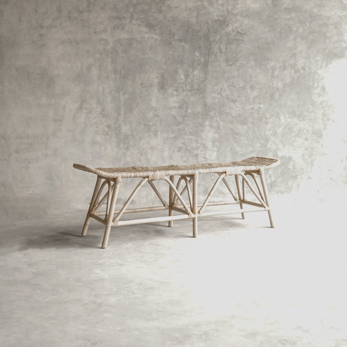 Woven rattan bench against a gray wall