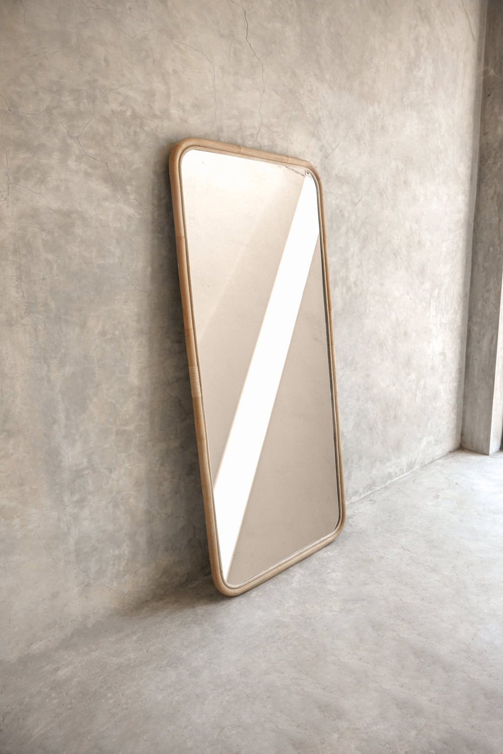 Modern rectangular mirror leaning against concrete wall